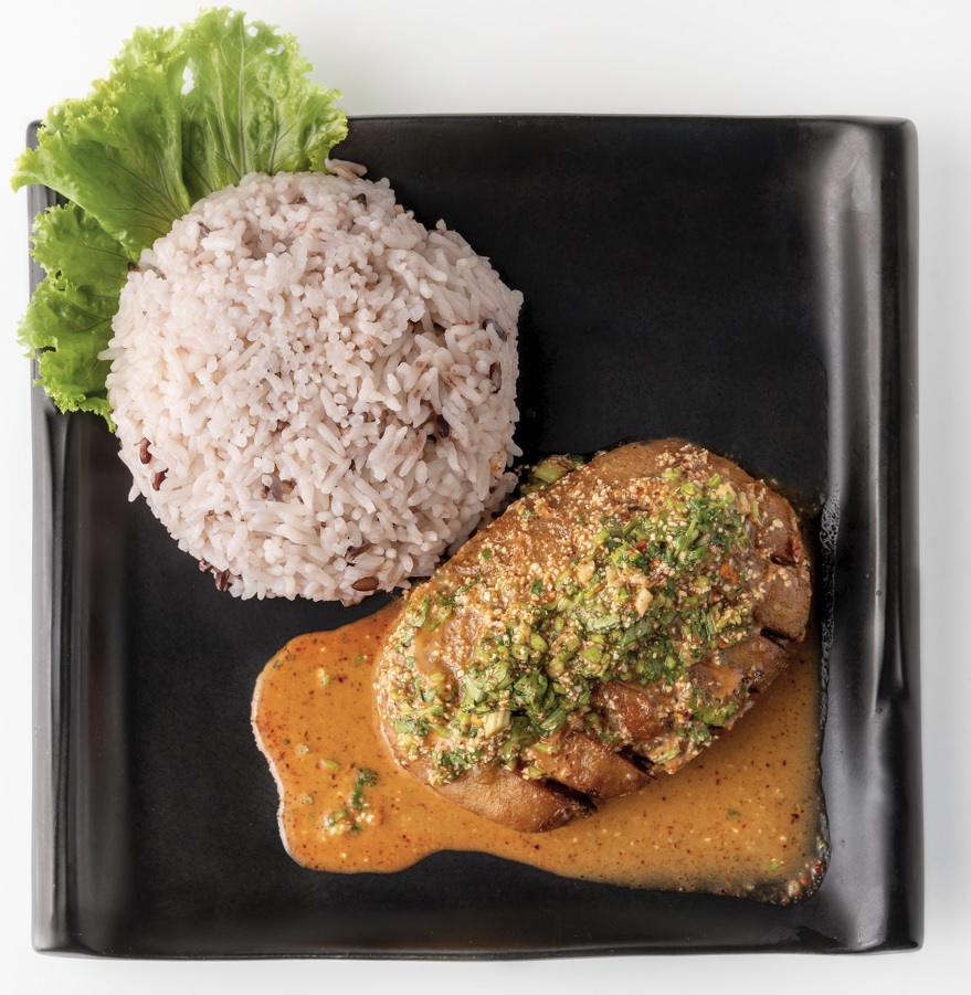 ข้าวไก่ย่างน้ำตกเจ ใส่ในจานสีดำ ของร้านโซวีแกน